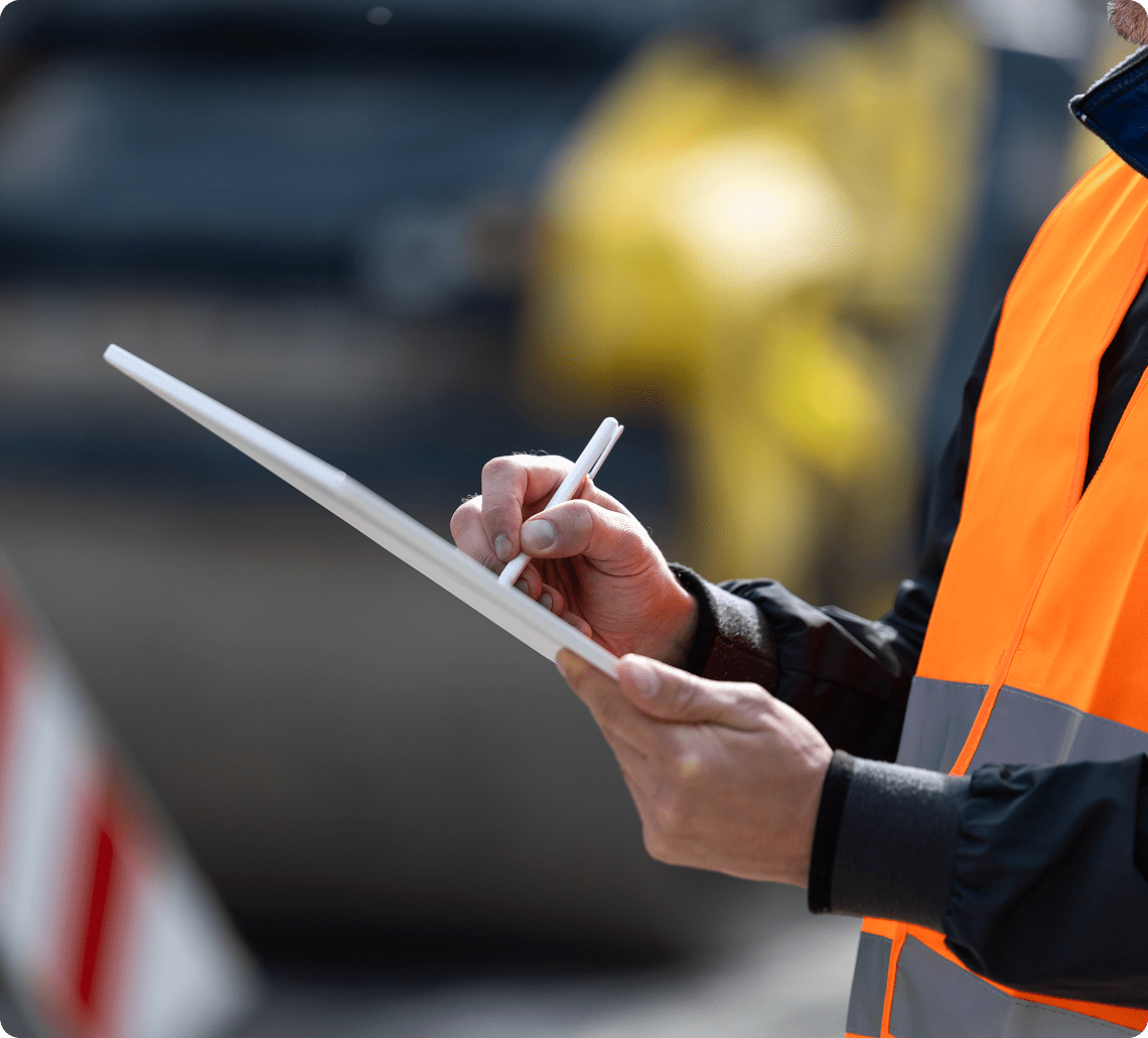 Construction worker writing on clipboard